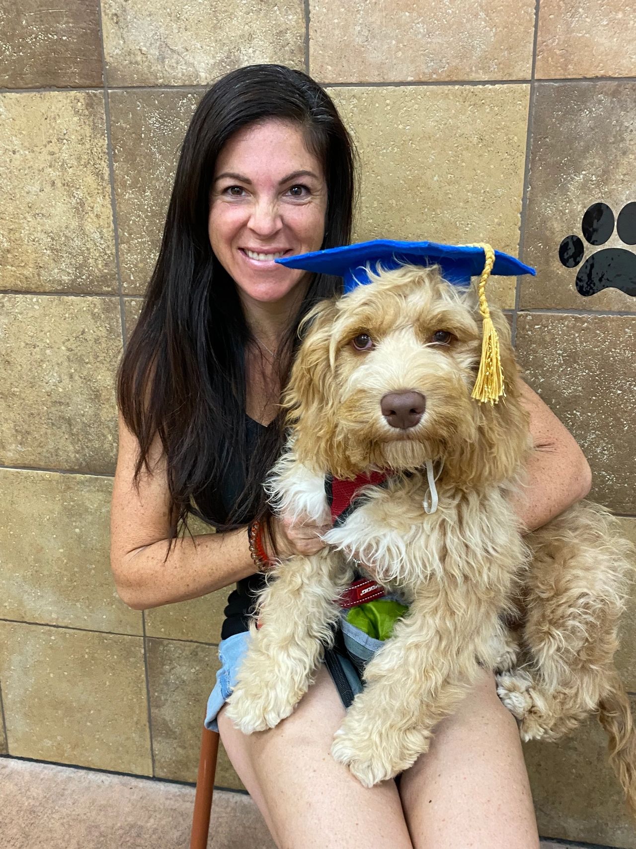 Woman holding a puppy wearing a graduation cap